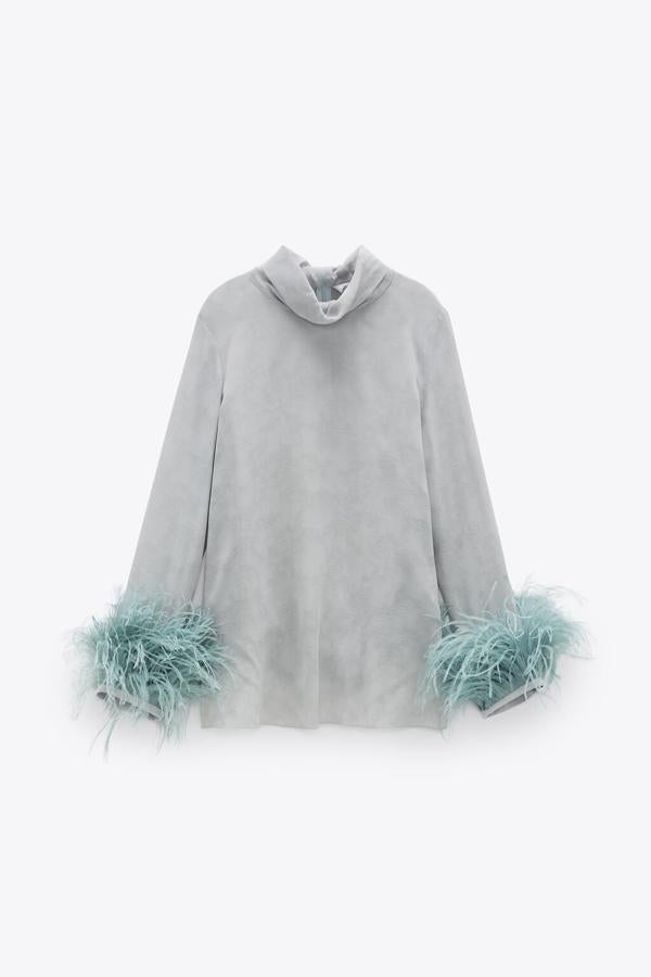De cuello subido y con aplicación de plumas en el puño, esta blusa con cierre de cremallera oculta en la costura de la espalda es de color gris perla y tiene un precio de 69,95 euros. Está disponible entre las tallas XS y XL.