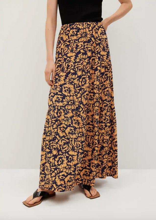En tejido fluido, con diseño acampanado estampado de fondo negro con flores en naranja pastel, esta falda midi de Mango viene con cintura elástica y detalle de volante en el frontal. Cuesta 29,99 euros y está disponible entre las tallas XS y XL.