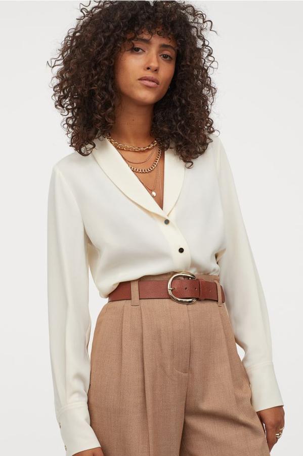 En tejido con caída y cuello esmoquin, esta blusa color crema, ligeramente entallada y con botones a contraste en color negro tiene escote de pico y mangas largas amplias. Cuesta 29,99 euros y está disponible en las tallas 38 y 44.