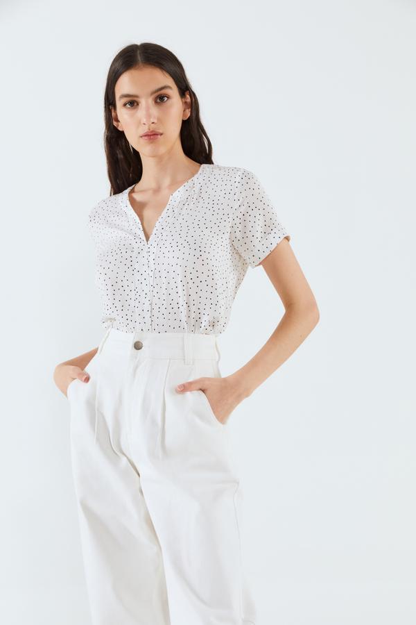 En color blanco con topos a contraste en negro, esta de Sfera con cuello de pico y manga corta tiene un precio de 13,99 euros y está disponible entre las tallas S y XL.