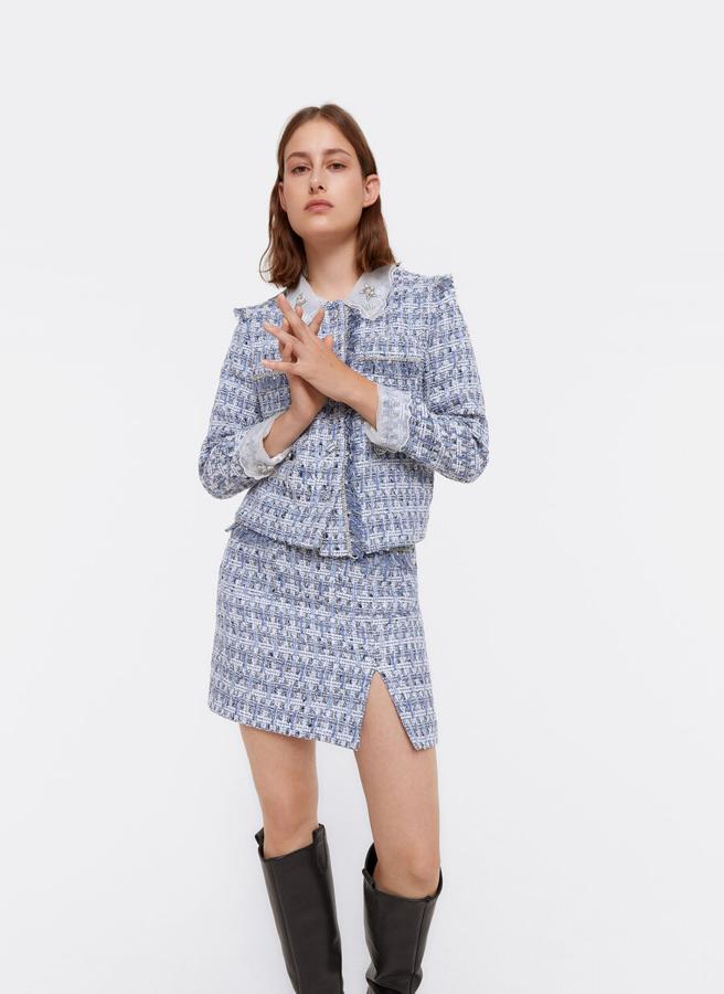 En Uterqüe han apostado por un tejido fantasía con detalles desflecados y decoración de strass compuesto por una  chaqueta corta con cuello desmontable que te soluciona cualquier look  (159 euros) y una falda corta con cintura alta (79 euros) en tonos azules y blancos.