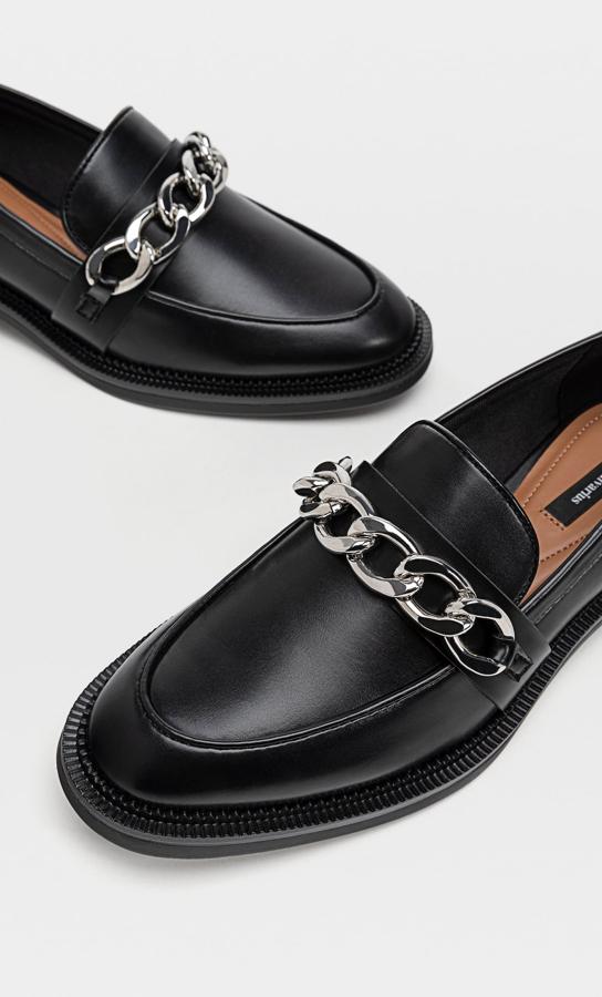 En Stradivarius hemos encontrado estos mocasines de color negro con cadena de tamaño medio en metalizada en color plata y con punta redonda. Tienen un precio de 25,99 euros y están disponibles entre los números 36 y 40.