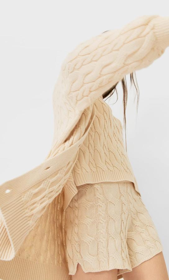 Stradivarius apuesta por el tres piezas de punto trenzado al combinar este conjunto de shorts (15.99 euros), jersey cropped y maxi cárdigan color crudo.