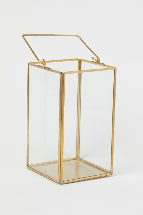 Disponible en dorado o negro, este portavelas de vidrio y metal con asa en la parte de arriba está indicado para velas gruesas y tiene un alto de 20 centímetros y un ancho de 12. Cuesta 17,99 euros.