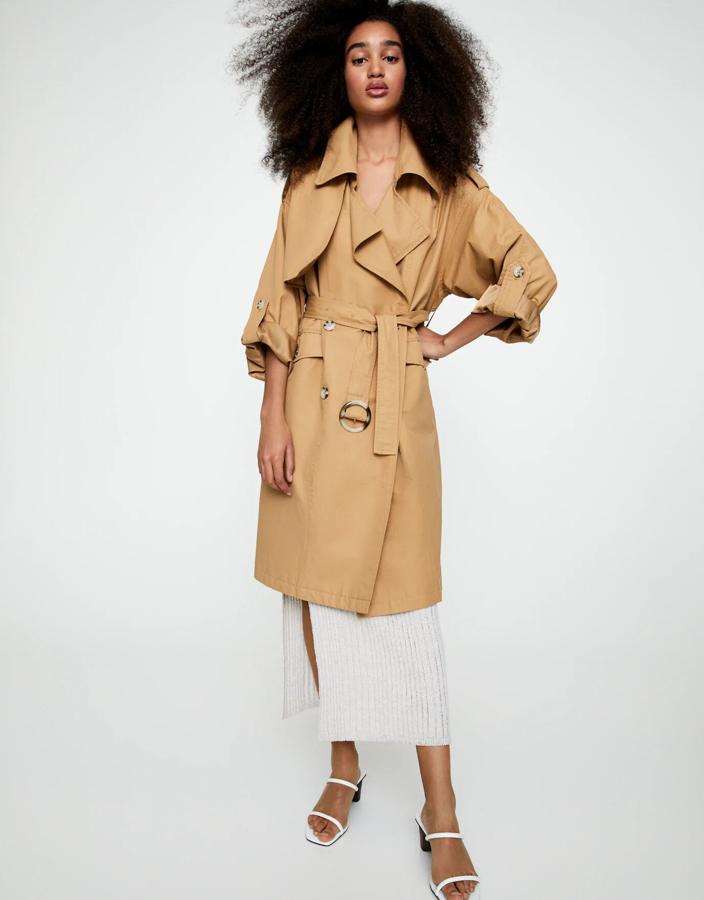 Este trench cruzado de silueta oversize está disponible en color camel o crudo. Con botones y bolsillos, tiene un precio rebajado de 25,99 euros.