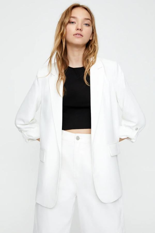 Con cuello smoking y bolsillos delanteros de tapeta, esta blazer sin botones confeccionada en tejido ligeramente elástico está disponible en blanco o en negro. Es de Pull & Bear y tiene un precio de 25,99 euros.