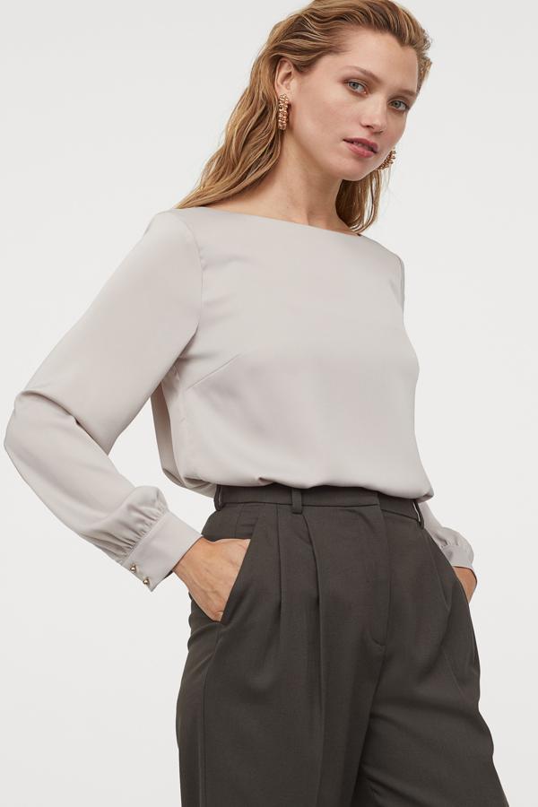 En color topo, esta blusa recta en crepé de satén y escote de barco cuenta con puños anchos con botones de metal. Es de H&M y tiene un precio de 19,99 euros.