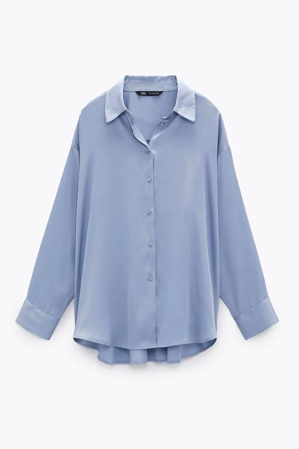 En Zara encontramos esta camisa satinada básica, disponible en azul celeste, blanco roto, negro o rosa claro. Con cuello solapa y manga larga, tiene un precio de 22,95 euros.