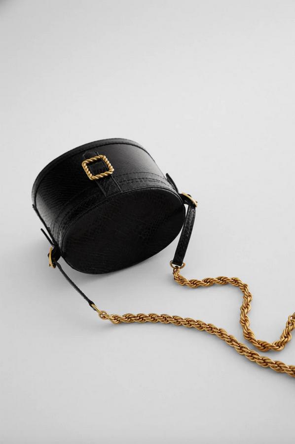 Cuerpo ovalado con estampado animal para este bolso en formato caja y color negro de Zara con detalle de hebilla metalizada en color dotado y asa de hombro con cadena en combinación de materiales. Cuesta 29,95 euros.