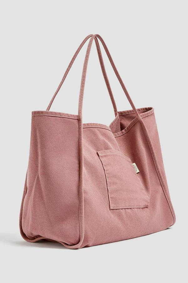 En color rosa (también disponible en gris), este bolso formato shopper de tejido lavado cuenta con detalle de bolsillo en la parte delantera y asas de hombro. Es de Pull & Bear y tiene un precio de 15,99 euros.