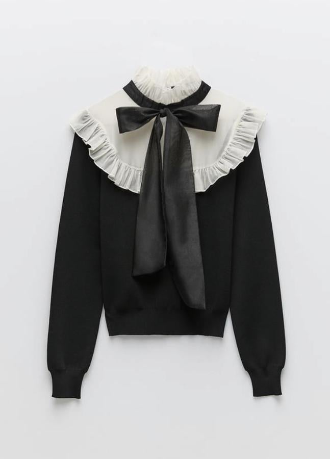 Jersey de punto en blanco y negro, con efecto babero con volante y lazo, de Zara (25,95 euros).
