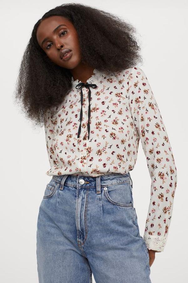 Estampado minimalista de flores rojas y granates para esta blusa blanca de H&M con cuello elevado corto con encaje de flores y lazada. Con cierre de botones frontal y mangas largas con puños sencillos decorados también con encaje. Cuesta 24,99 euros y está disponible entre las tallas 32 y 46.