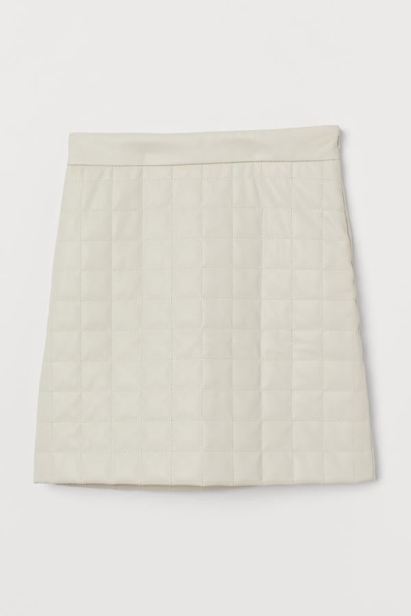 Esta falda corta guateada en piel sintética de color blanco cuenta con cintura alta y cremallera oculta en un lateral. Es de H&M y tiene un precio de 29,99 euros.