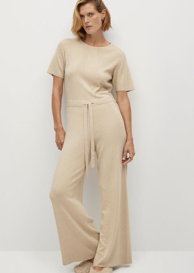 En color crudo y en tejido de punto, este mono largo de manga corta con cuello redondo y cierre de lazos ajustables tiene un precio de 49,99 euros. Es de Mango.