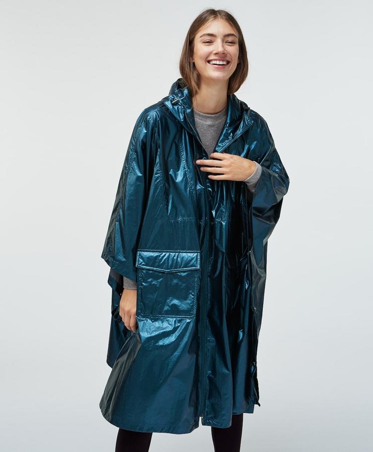 Este chubasquero estilo capa en azul metalizado es toda una prenda-statement. Es ajustable, tiene capucha y su tejido es ultraligero. El cierre con cremallera garantiza la protección frente al viento. Puedes conseguirlo en dos tallas: la SM y la ML.