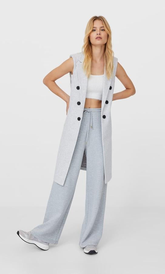 En color gris, con cuello y solapa con manga sisa, este chaleco largo de Stradivarius viene con cierre cruzado con botones a contraste en negro y bolsillos delanteros de vivo. Podemos encontrarlo entre las tallas XS y XL por 35,99 euros.