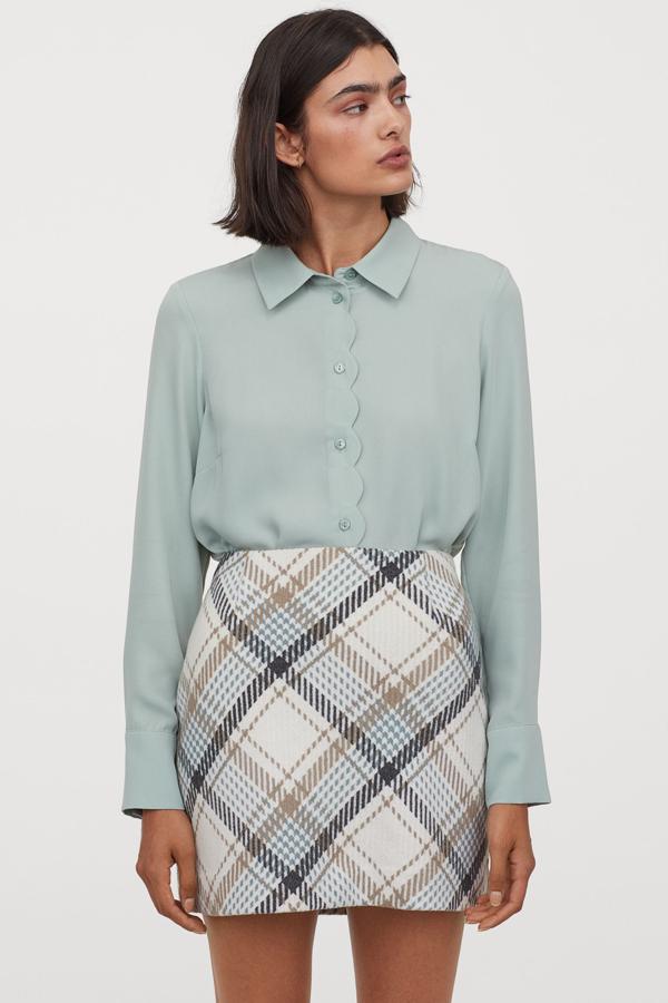 Confeccionada en lana y poliéster reciclados, esta minifalda de H&M de talle alto viene en color blanco con estampado de cuadros en azul y gris. Tiene un precio de 29,99 euros y está disponible entre las tallas 32 y 50.