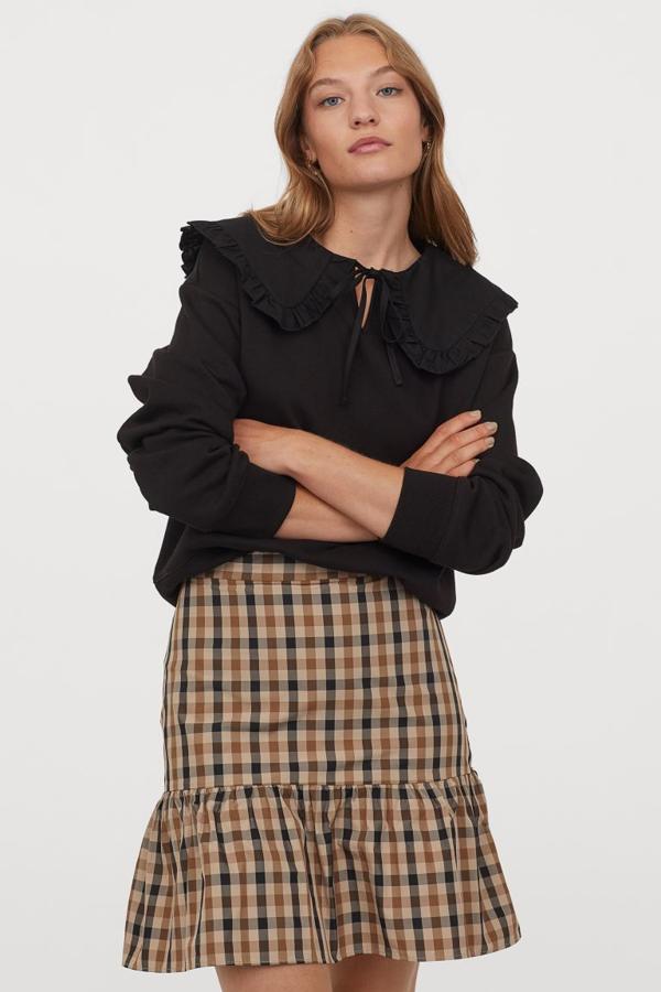 En H&M hemos encontrado esta falda corta de talle alto, ceñida en la parte alta y con costura fruncida en el bajo para darle volumen. De cuadros negros y marrones sobre fondo beige, cuesta 19,99 euros y está disponible entre las tallas 32 y 50.