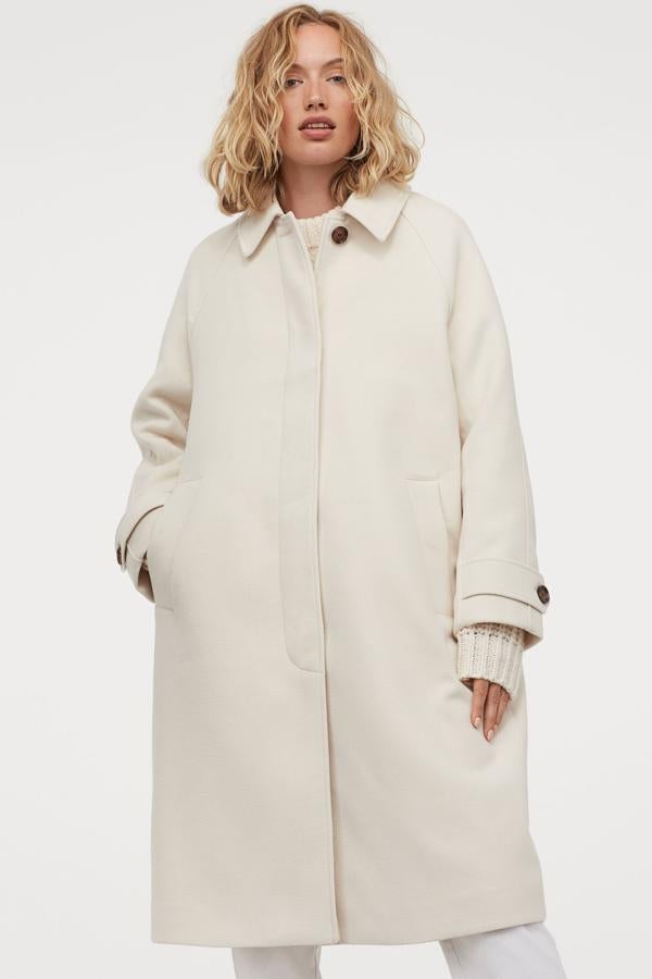 Abrigo de H&M en blanco, de patrón tipo inglés y botones de efecto piel (79,99 euros).