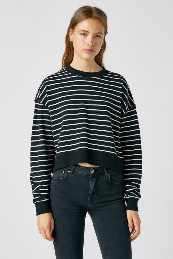 En color negro con finas rayas blancas, este jersey básico confeccionado en algodón y con cuello redondo en de Pull & Bear y tiene un precio de 9,99 euros.
