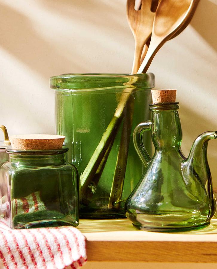 En vidrio reciclado postconsumo de color verde, este set de accesorios de cocina está formado por dos botes con tapón de corcho y de dos tamaños diferentes (9,99 euros y 12,99 euros), un bote para utensilios (19,99 euros) y una aceitera (9,99 euros).