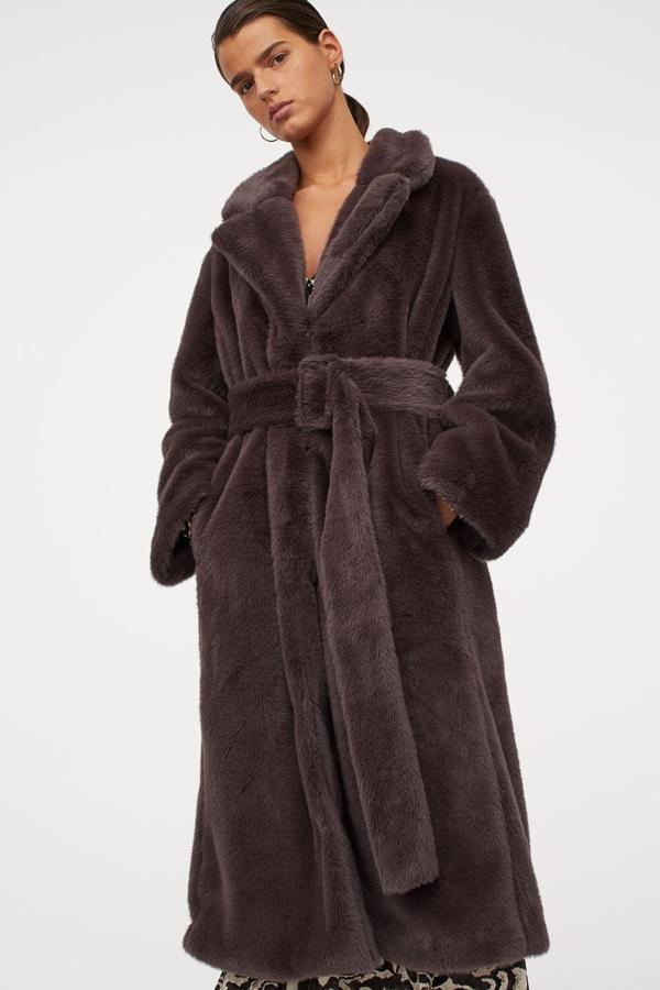 Este abrigo midi en pelo sintético de color gris oscuro cuenta con cierre oculto de corchete y cinturón ancho con hebilla revestida. Es de H&M y tiene un precio de 99 euros.