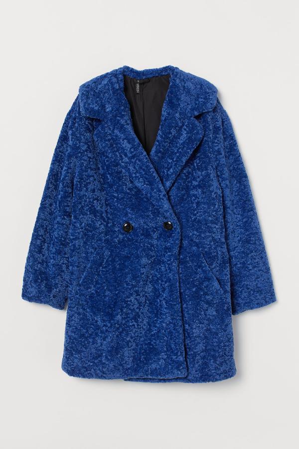 Con doble botonadura, esta chaqueta de pelo sintético en color azul también está disponible en negro y beige claro. Con solapas y hombros caídos, es de H&M y tiene un precio de 69,99 euros.