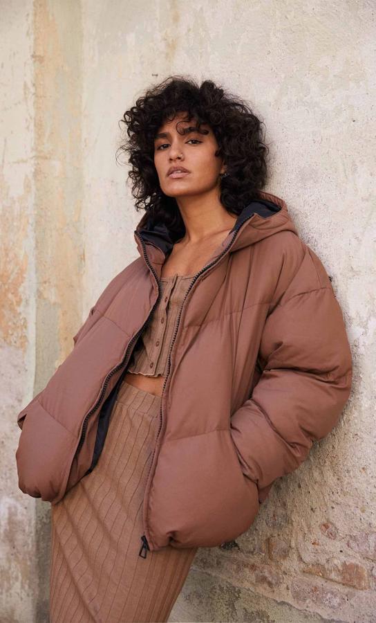 Diseño padding oversize en color terracota con capucha, mangas largas y cierre de cremallera a contraste. Cuesta 35,99 euros y está disponible entre las tallas XS y XL.