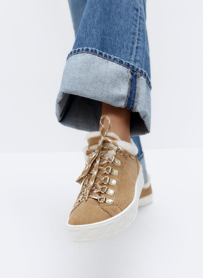 Suela plana en color blanco para esta zapatilla en camel en corte de piel de vacuno acabado en serraje con forro de piel de pelo de cordero en el tobillo. Con cierre de cordones de estilo montañés, cuestan 99 euros y están disponibles entre los números 35 y 42.