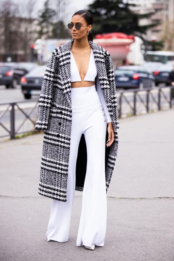 La sastrería tradicional masculina se convierte en una apuesta segura cuando se invierten los códigos y se plasma el estampado de pata de gallo en un abrigo tres cuartos recto que se combina con un look de dos piezas blanco.