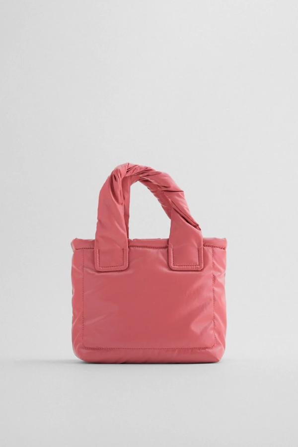 Este bolso formato mini shopper de color rosa también está disponible en negro. Con cuerpo acolchado con pespuntes, cuenta con asa de mano entrelazadas y asa de hombro ajustable y extraíble. Tiene un precio de 19,95 euros.