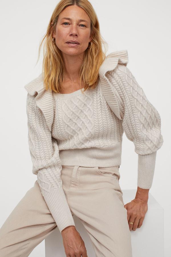 Este jersey en punto trenzado suave de color beige grisáceo cuenta con escote cuadrado, volante ancho de encaje en los hombros y mangas amplias. Tiene un precio de 29,99 euros.