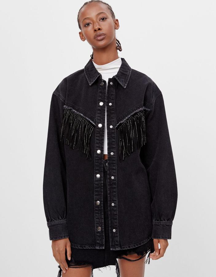 En color negro, esta sobrecamisa larga con botones plateados y detalle de flecos tiene un precio rebajado de 23,99 euros.