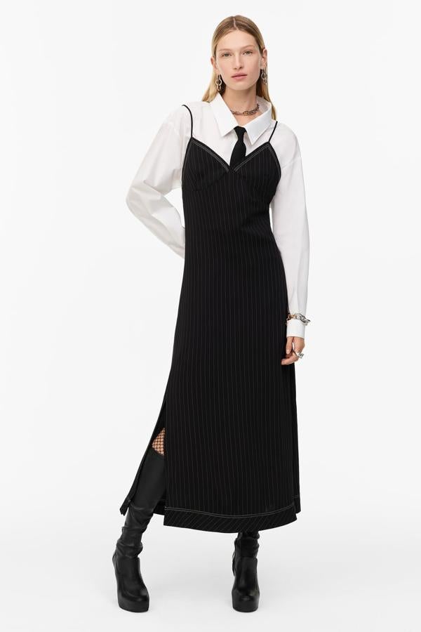 No descartes los vestidos de tirantes porque la temperatura no acompaña, llevarlo sobre una prenda de manga larga puede ser una solución infalible. Si además es una camisa, puedes dejar que por el escote asome también una corbata para darle un decidido toque noventero. Vestido tipo enagua con estampado de raya diplomática, escote de pico y tirantes (79,95 €), de Zara.