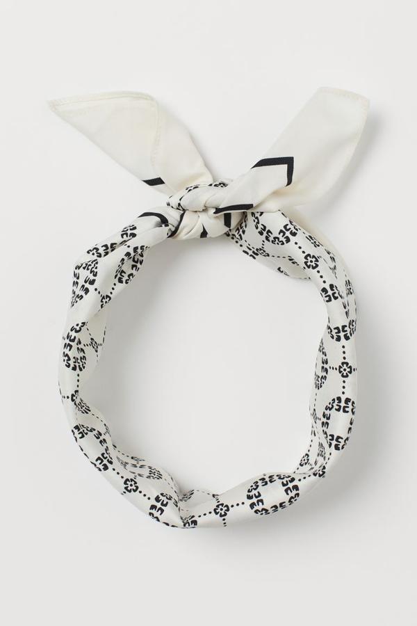 Fondo blanco con estampado de motivos en negro para este pañuelo de satén de H&M que podemos usar como cinta o para proteger toda la cabeza. Está confeccionado en poliéster reciclado y cuesta 7,99 euros.