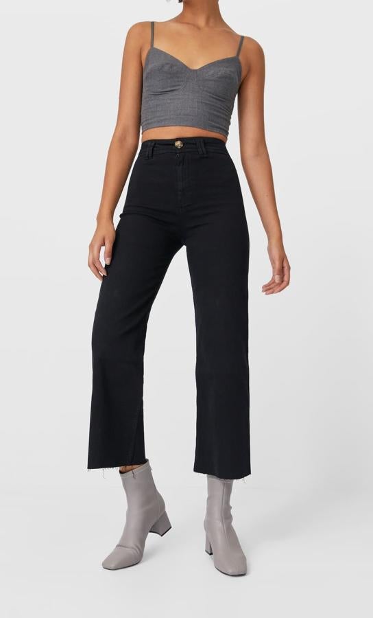En color negro, con tiro alto y cinco bolsillos, este pantalón culotte de Stradivarius en sarga seamless viene con pernera ancha y bajos deshilachados. Tiene un precio de 25,99 euros y está disponible entre las tallas 32 y 42.