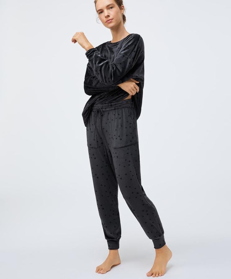 En gris antracita con estampado de estrellitas, este pijama polar de Oysho viene con sudadera de manga larga y cuello redondo con puño en las mangas y pantalón con puño en el bajo y cintura ajustable con goma elástica y cierre de cordón con bolsillos laterales. Cuesta 35,98 euros y está disponible entre las tallas XS y XL.