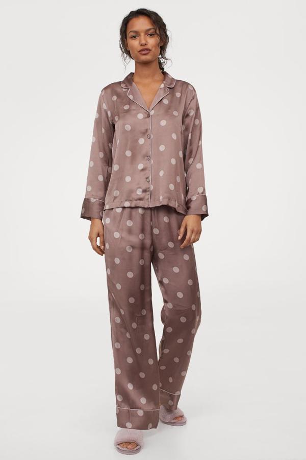 En beige grisáceo con estampado de lunares, este pijama de dos piezas en satén suave es de H&M y viene con camisa de manga larga con cuello, escote de pico y cierre de botones y pantalón con elástico revestido en la cintura y perneras amplias en corte recto. Cuesta 29,99 euros y está disponible entre las tallas S y XL.