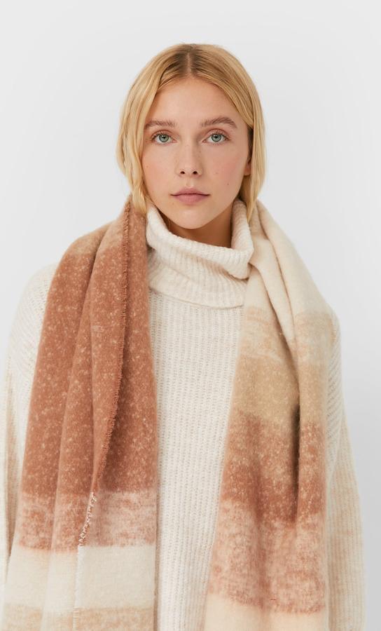 Diseño degradado de rayas horizontales en beige y marrón claro para esta bufanda de Stradivarius con extremos acabados en flecos que tiene un precio de 15,99 euros.