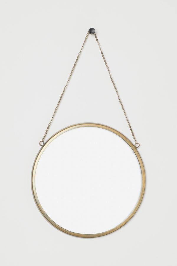 Combinar espejos pequeños y redondos (puedes poner varios en la misma pared a diferentes alturas) puede darle a una habitación un efecto divertido al tiempo que aportas luz al conjunto. Este espejo para golgar con cadena de H&M Home parece diseñado para llevar a la práctica este truco (19,99 euros).