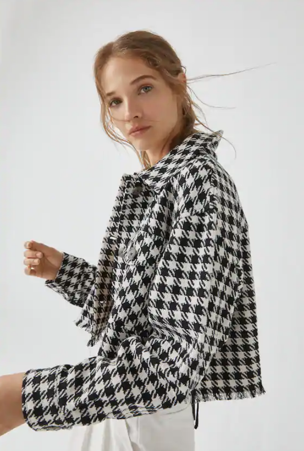 Sobrecamisa 'cropped' con estampado de cuadros blancos y negros de Pull&Bear (29,99 euros). Lleva manga larga, cuello clásico, bolsillos delanteros de tapeta y detalle de flecos en el bajo.