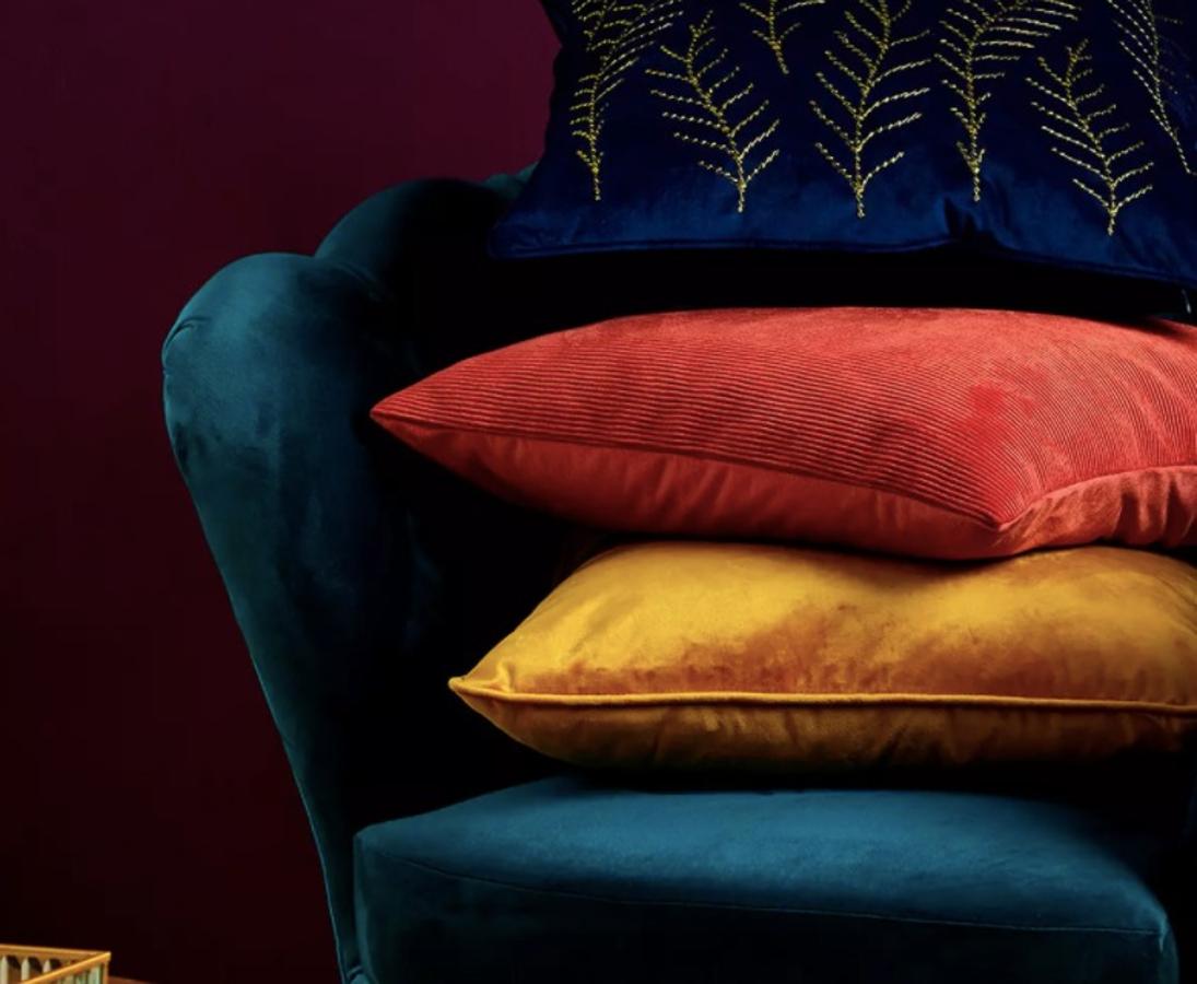 Funda de cojín de terciopelo azul 3,50 €, funda de cojín de terciopelo amarillo 3,50 € y cojín de flores 12 €.