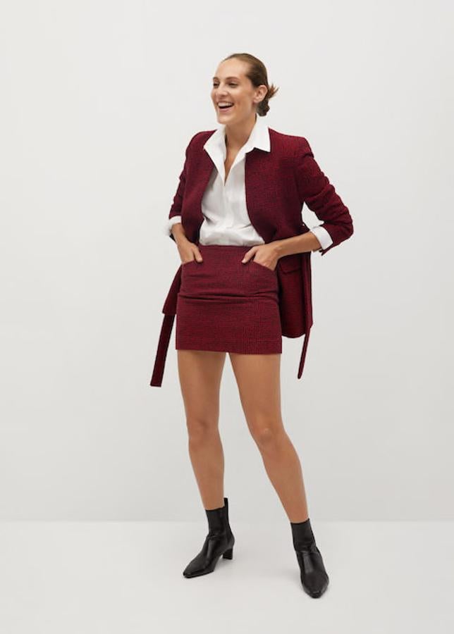 Americana, minifalda, camisa blanca masculina y botines de tacón midi, todo de Mango.