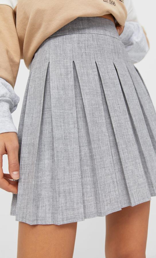 En color gris liso, esta falda mini de tiro alto con detalle de tablas es de Stradivarius y tiene un precio de 19,99 euros. Podemos encontrarla entre las tallas XS y XL.