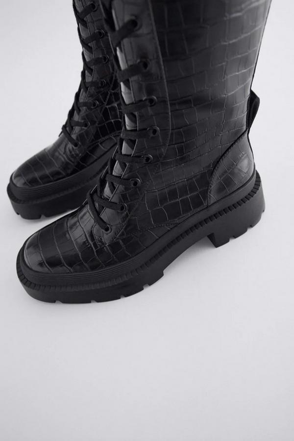 Con suela track plana y tirador en la parte trasera inferior, estas botas negras de Zara con cierre de cordones y cremallera en efecto piel cuestan 49,95 euros y están disponibles entre los números 35 y 42.
