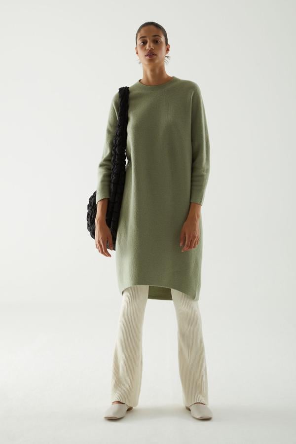 Un look puramente minimalista, de líneas depuradas, formado por un vestido de punto con cuello redondo y bajo asimétrico y pantalones anchos de pana, todo de COS.