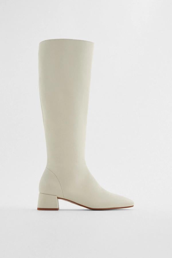 De caña alta y con punta cuadrada, esta bota alta de piel en color blanco crudo y tacón de cuatro centímetros cuenta con cierre mediante cremallera interior y tiene un precio de 89,95 euros.