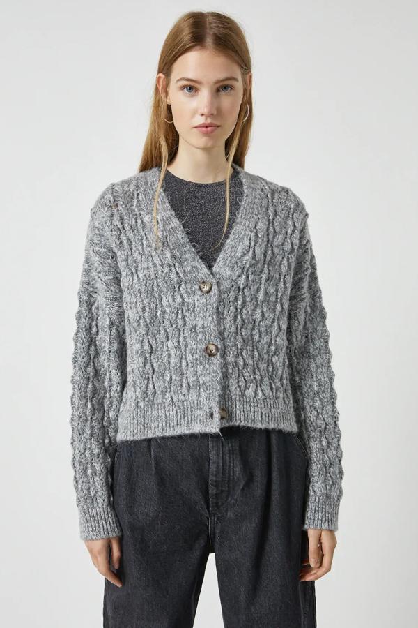 Esta chaqueta de punto en color gris y con detalle de calados cuenta con botones en la parte delantera y tiene un precio rebajado de 20,79 euros. Es de Pull & Bear.