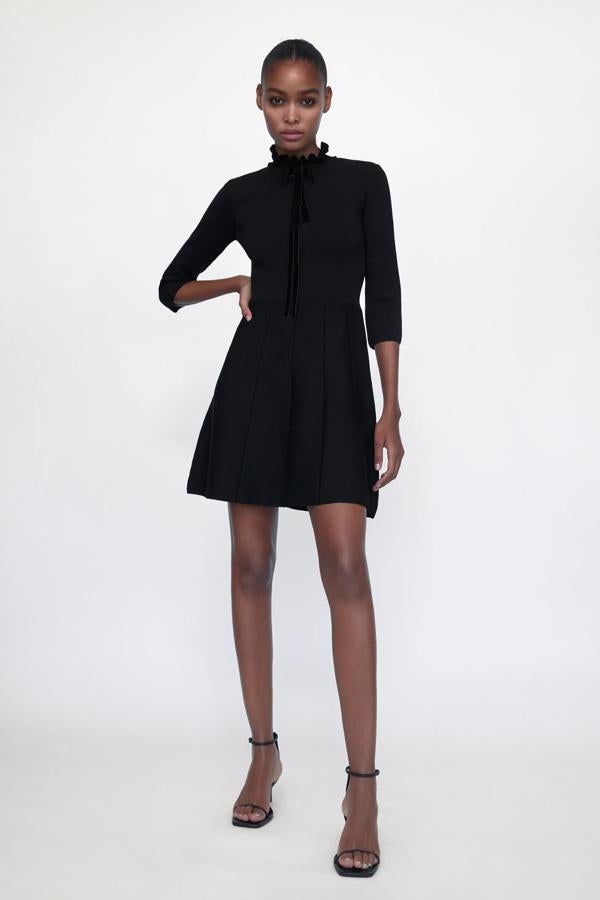 En color negro, este vestido de punto con cuello subido con volante y lazo cuenta con manga por debajo del codo y bajo acabado en evasé. Tiene un precio de 29,95 euros.