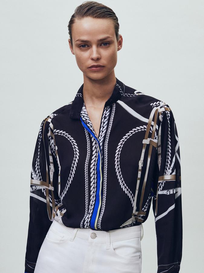Con detalle de lazada extraíble en el cuello, esta camisa de fondo negro con estampado de cadenas en beige, blanco y azul viene con corte recto, cierre mediante botonadura frontal oculta por tapeta y puños abotonados. De 69,95 euros ha pasado a costar 55,95 euros y está disponible entre las tallas 34 y 44.